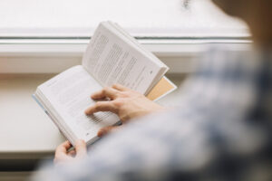 crop man reading book near window
